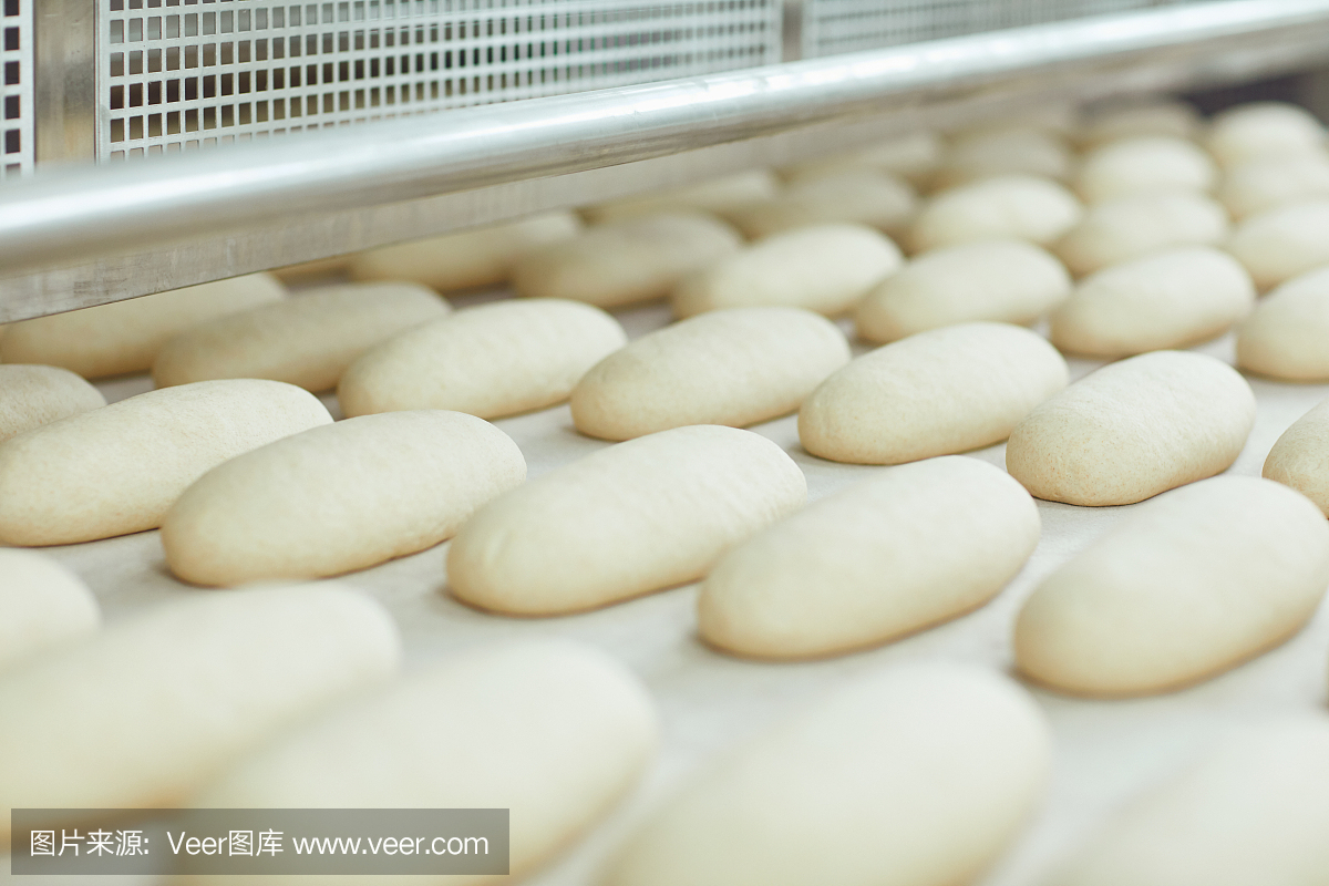 面包店的自动设备生产线上正在生产生面包。